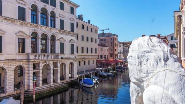 Un canal con edificios a un lado y una estatua al frente.