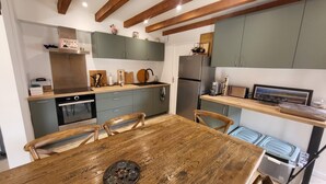 Una cocina con mesa de madera, armarios y refrigerador.