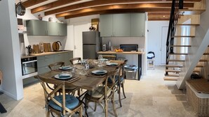Una cocina moderna con comedor, vigas de madera y una escalera.