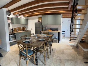 Eine moderne Küche mit Essbereich, Holzbalken und einer Treppe.