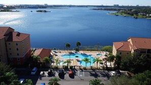 Un hotel con piscina, estacionamiento y vistas a una amplia extensión de agua.