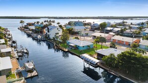Een jachthaven met aangemeerde boten, huizen aan het water en palmbomen.