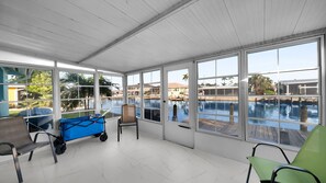 Ein Wintergarten mit großen Fenstern mit Blick auf einen Pool und einen Yachthafen.