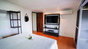 A hotel room with a bed, a TV, a wardrobe, and a balcony. - Tuba Flat: Ground Floor with Pool and Tropical Garden (Fernando de Noronha)