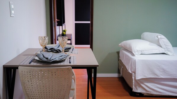 A small room with a bed, a table with a chair, and a window.