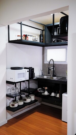 A compact kitchen with a microwave, coffee maker, and a sink.