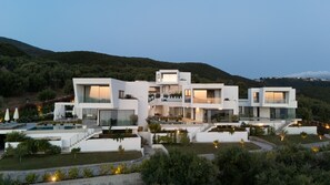 A modern multi-story house with a pool, surrounded by greenery and hills. - Syvana Exquisite Villas III (Syvota)