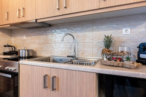Eine Küche mit Holzausbau, einem Edelstahlspülbecken, einem Herd und einer Arbeitsplatte mit Obstkorb und Ananas.