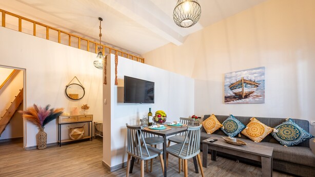 Una sala de estar moderna con comedor, una escalera y un televisor de pantalla plana montado en la pared.