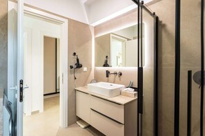 Een moderne badkamer met een grote spiegel, een wastafel en een douchehoek.