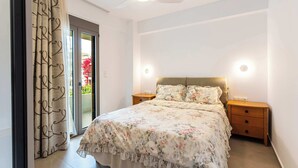 Un dormitorio con cama, ventilador de techo, mesita de noche y puerta corrediza de vidrio.