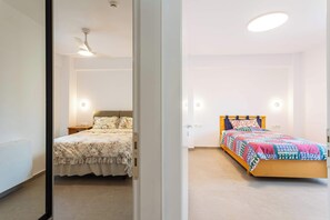 Een slaapkamer met een bed, nachtkastje, plafondventilator en een wandlamp.