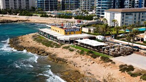 Een restaurant aan de kust met terras, een zwembad en uitzicht op zee.
