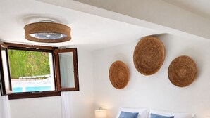 Een keurig opgemaakt slaapkamer met een bed, bedlampen, een raam met uitzicht en decoratieve wandkunst.