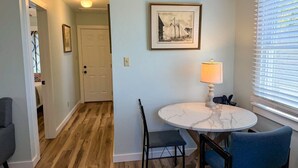 Un coin repas avec une table ronde, des chaises, une lampe et un tableau encadré au mur.