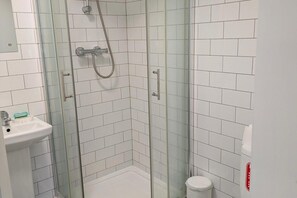 A bathroom with white tiled walls, a glass shower enclosure, a sink with a mirror, and a toilet. - Corby Lodge Park 4-double Bed House Sleeps 8 (Corby)