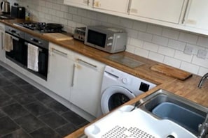 A kitchen with a washing machine, a microwave, and a sink. - Corby Lodge Park 4-double Bed House Sleeps 8 (Corby)