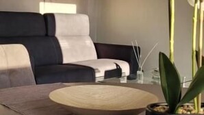 En moderne stue med en sofa, et rundt bord og en orkidé i potte.