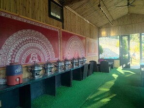 A room with a long table, decorative wall panels, and a view of the outdoors. - Bhimtal Hotel nr. Bhowali Range Arahnyam (Bhimtal)