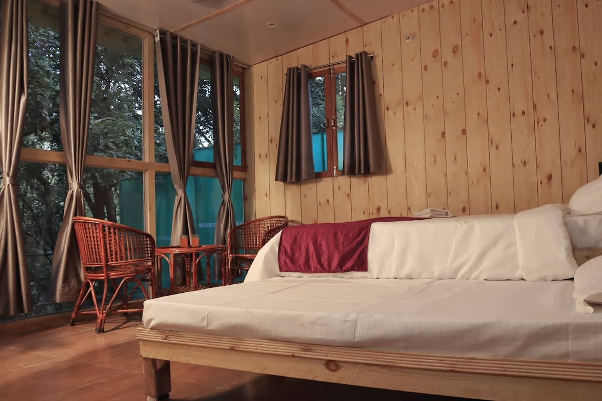 A wooden-paneled room with a bed, a chair, and a window with curtains.