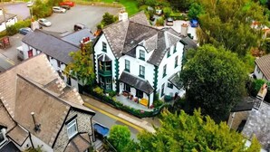 Um edifício tradicional com fachada verde e branca marcante, situado em um ambiente rural exuberante e verdejante.
