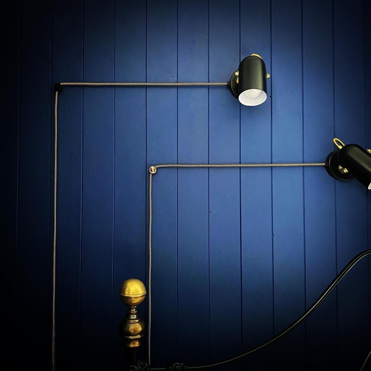 Un mur bleu, une lampe noire et un heurtoir de porte en laiton.