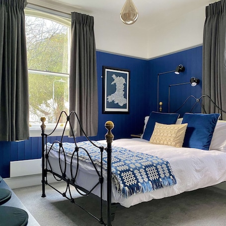 A bedroom with a bed, a window, a map on the wall, and a bedside table.. Crafnant House - Bed & Breakfast