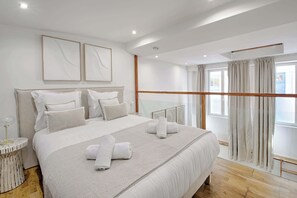 Een moderne hotelkamer met een groot bed, een glazen balustrade en uitzicht op de stad.