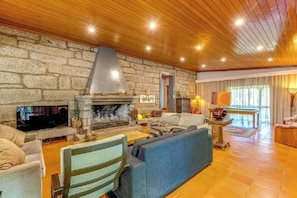 Un salón acogedor con chimenea de piedra, techo de madera y asientos cómodos.