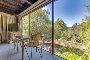 A room with a large window, a table, chairs, and a television.