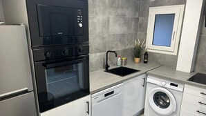 Une cuisine moderne équipée d’un four encastré, d’un lave-vaisselle et d’une machine à laver.