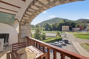 Un balcone con un arco in pietra che si affaccia su un'area di parcheggio e un pendio con edifici.