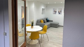 Un salon moderne avec un canapé gris, des fauteuils jaunes et une table blanche.