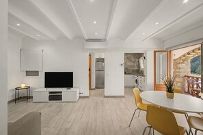 Un soggiorno moderno con una TV a schermo piatto, un'area pranzo con sedie gialle e una cucina con parete in pietra.