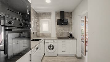 A compact kitchen with a built-in oven, a washing machine, and a coffee machine.