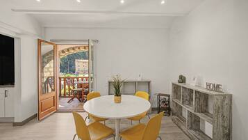Un comedor moderno con una mesa redonda, sillas amarillas y vistas a una terraza exterior a través de un ventanal.