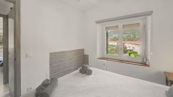 Un dormitorio con una ventana grande, un radiador y una cama bien hecha.