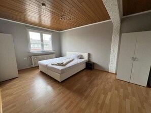 Ett sovrum med ett träpanelat tak, en säng, ett fönster och en garderob.