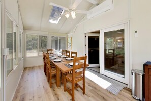Ein Essbereich mit einem langen Holztisch, Stühlen und einem Deckenventilator.
