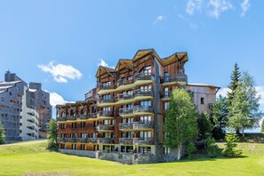 A multi-story hotel with balconies, a stone foundation, and a clear sky. - Neva- L'Écrin de la Falaise - Avoriaz (Morzine)
