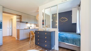 Ein modernes Schlafzimmer mit Bett, Schminktisch und Blick auf die Küche.