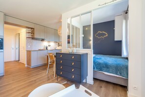 A modern bedroom with a bed, a dresser, and a view of the kitchen. - Neva- L'Écrin de la Falaise - Avoriaz (Morzine)
