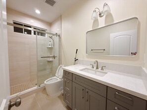 A modern bathroom with a glass-enclosed shower, a toilet, a sink with a mirror, and a vanity with drawers. - Cozy 2-bedroom house No Living room (San Gabriel)