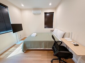 A small, neatly arranged bedroom with a bed, a desk, a chair, a TV, and an air conditioner. - Cozy 2-bedroom house No Living room (San Gabriel)