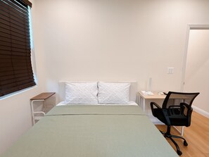 A bedroom with a bed, a chair, a nightstand, and a window with blinds. - Cozy 2-bedroom house No Living room (San Gabriel)