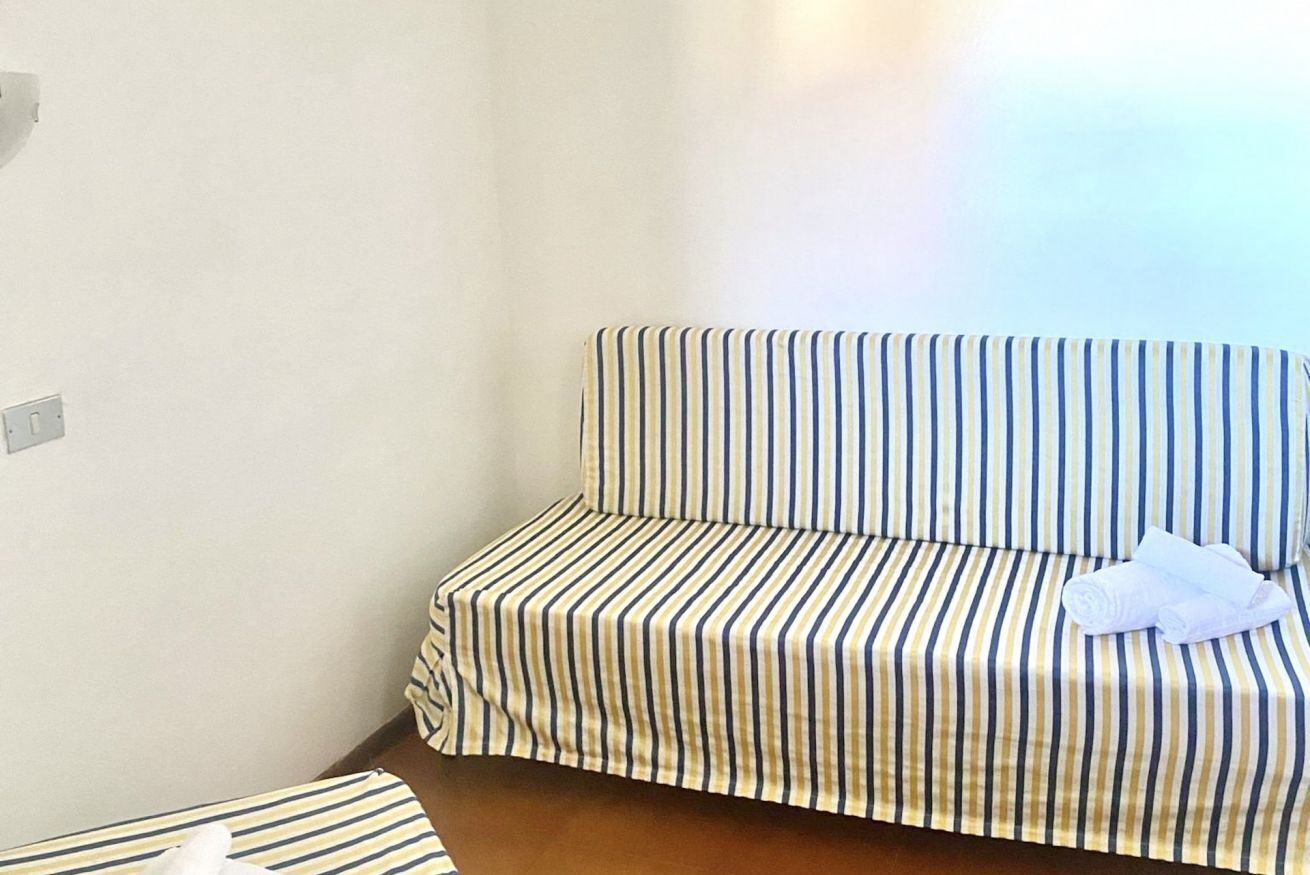 A striped sofa in a room with a plain wall and a light switch.
