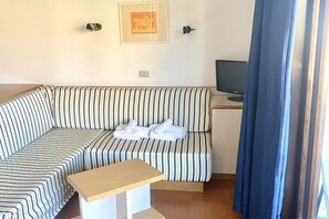 Ein gestreiftes Sofa mit einem kleinen Tisch, einem Fernseher und einem gerahmten Bild an der Wand.