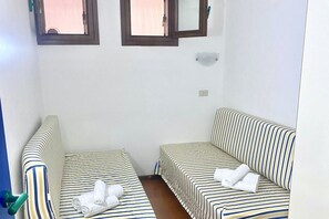 Ein kleiner, sauberer Raum mit zwei Einzelbetten, einem Fenster und einem Spiegel.