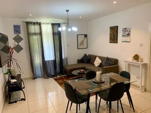 Ein modernes Wohnzimmer mit einem Glastisch, schwarzen Stühlen, einem braunen Sofa und einem weißen Konsolentisch.