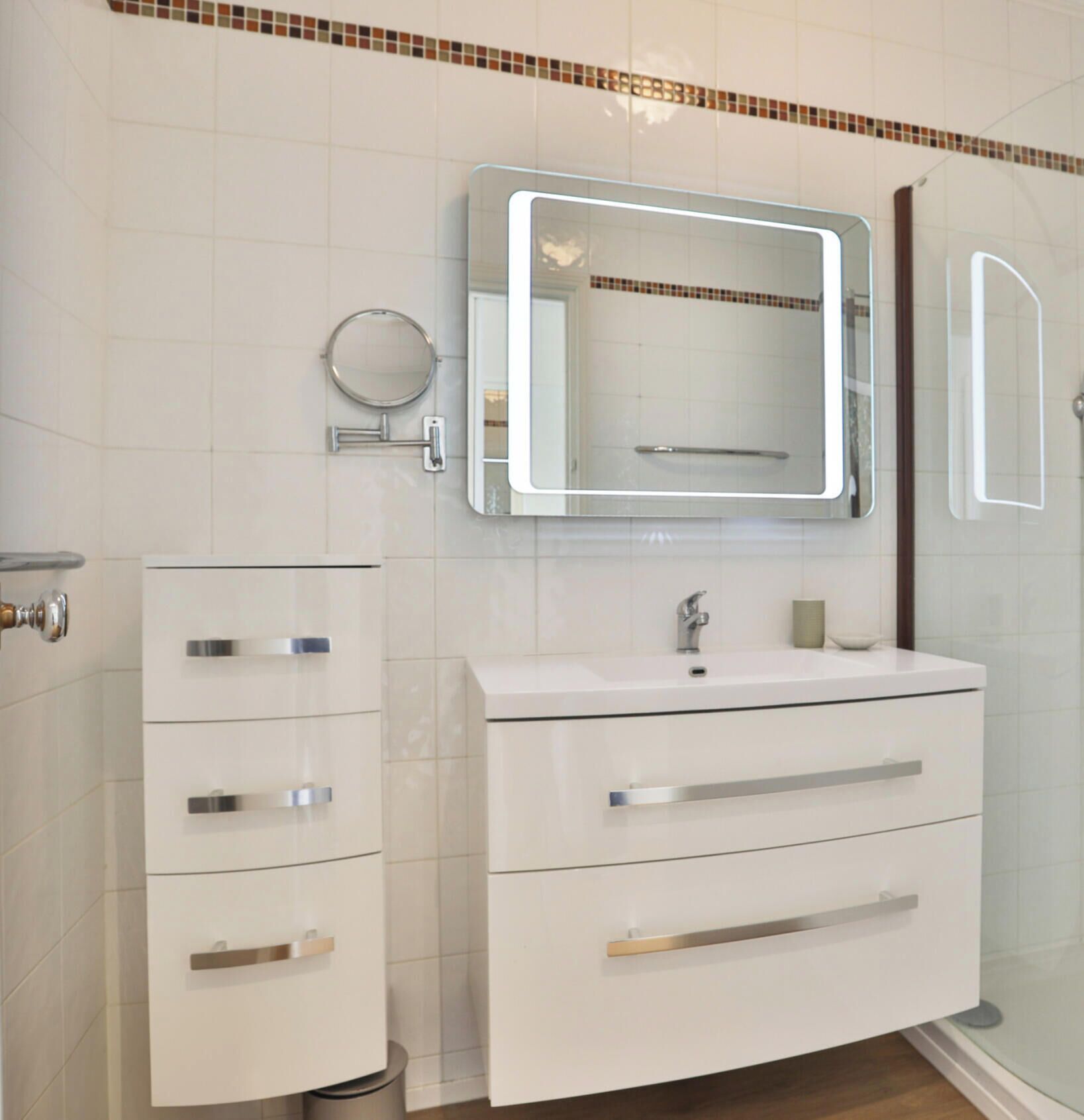 A modern bathroom with a white vanity, a mirror, and a shower.